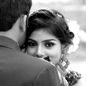 Close-up black and white portrait of a bride embracing her groom outdoors.